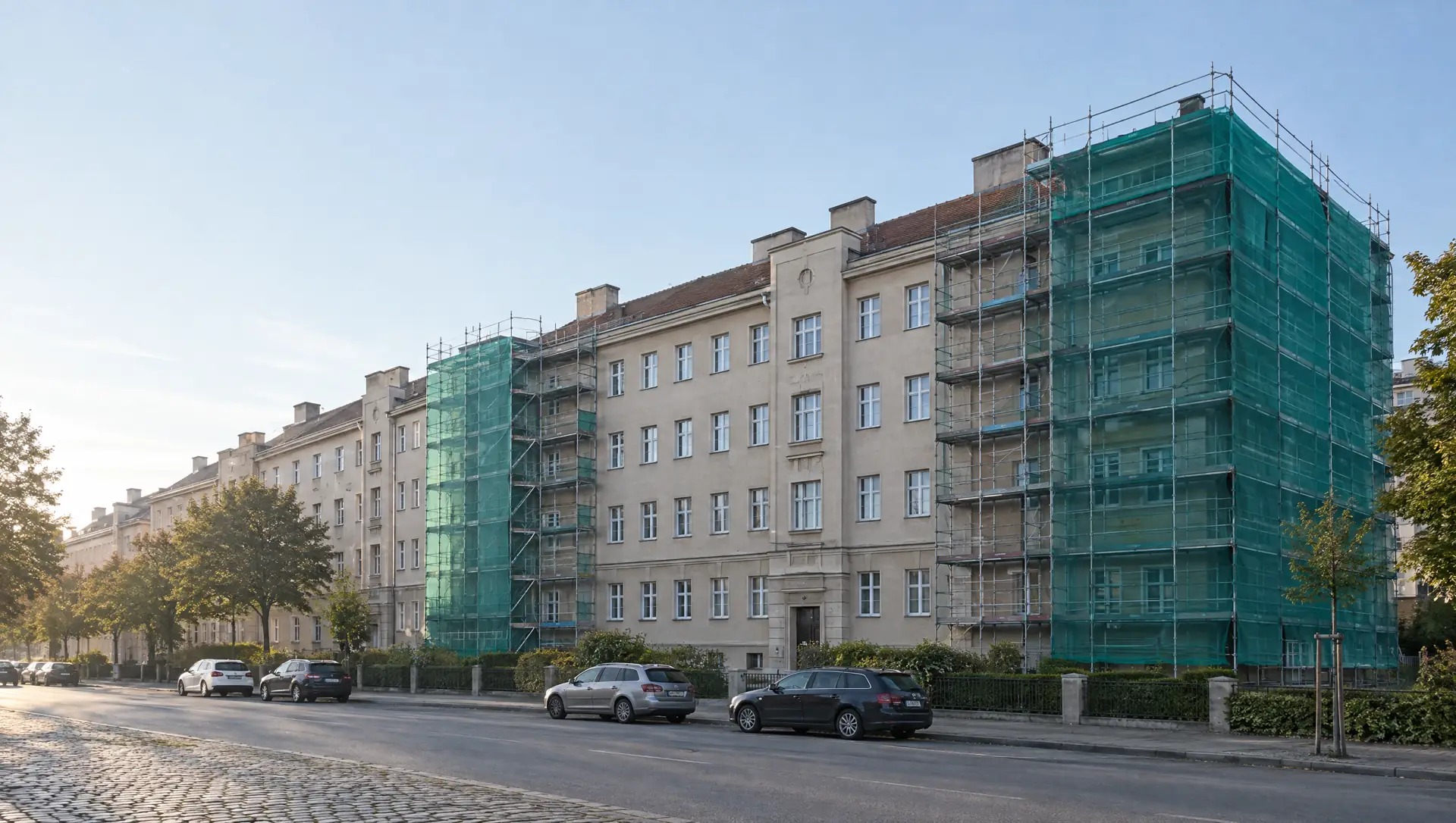 Illustration: Wiener Gemeindebau während der Sanierung, eingerüstet, am frühen Morgen